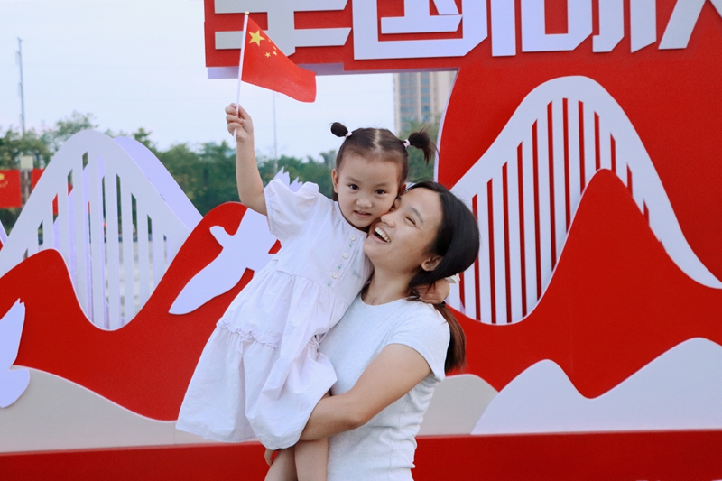 母女俩在国庆主题展板前拍照。韦新娜摄