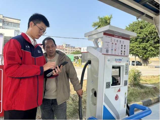 圖為中石化廣西公司工作人員指導車主使用“易捷加油”小程序充電。
