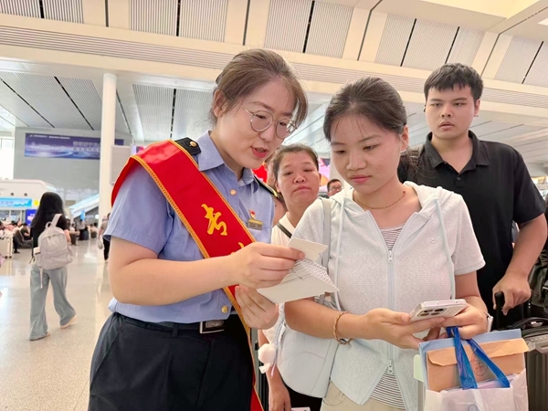 图为南宁东站客运值班员秦蓉蓉向学生专列旅客发动纪念票根。于莉摄