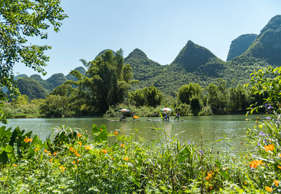游客在遇龙河上乘坐竹筏，感受山水之美。