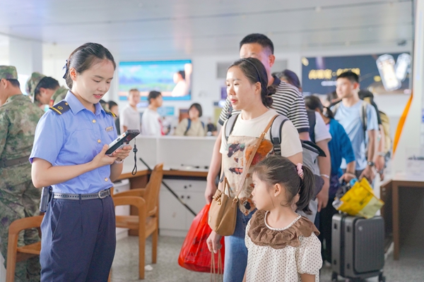 图为百色站客运值班员为进站旅客提供服务。秦塬棋摄