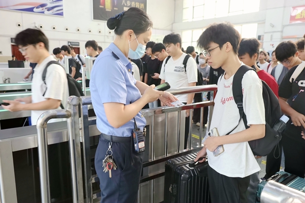 永福南站工作人员为学生旅客核验乘车信息。邓晓斌摄