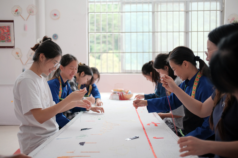 大学生和绣娘学习刺绣。