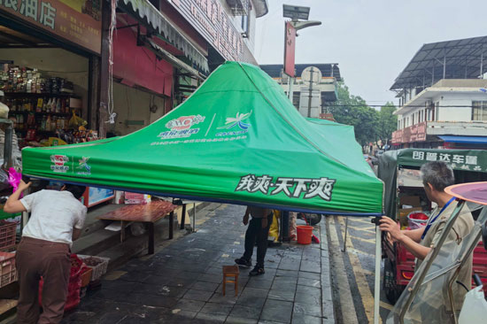 工作人员劝导商户清理占道帐篷，整治沿街占道经营