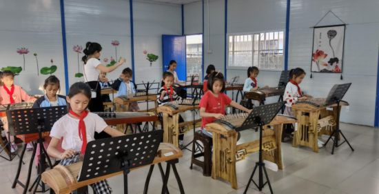 西乡塘小学古筝社团的同学们在古筝室里用他们的手指拂过琴弦，弹出美妙的旋律。