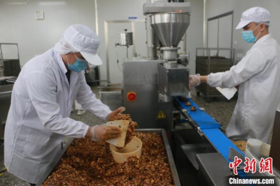 工人将酸笋、酸豆角、螺蛳肉等螺蛳粉原料，调制成螺蛳粉月饼的馅料。林馨 摄