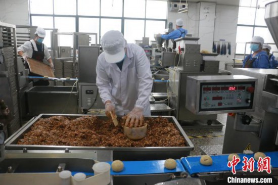 工人将酸笋、酸豆角、螺蛳肉等螺蛳粉原料，调制成螺蛳粉月饼的馅料。林馨 摄
